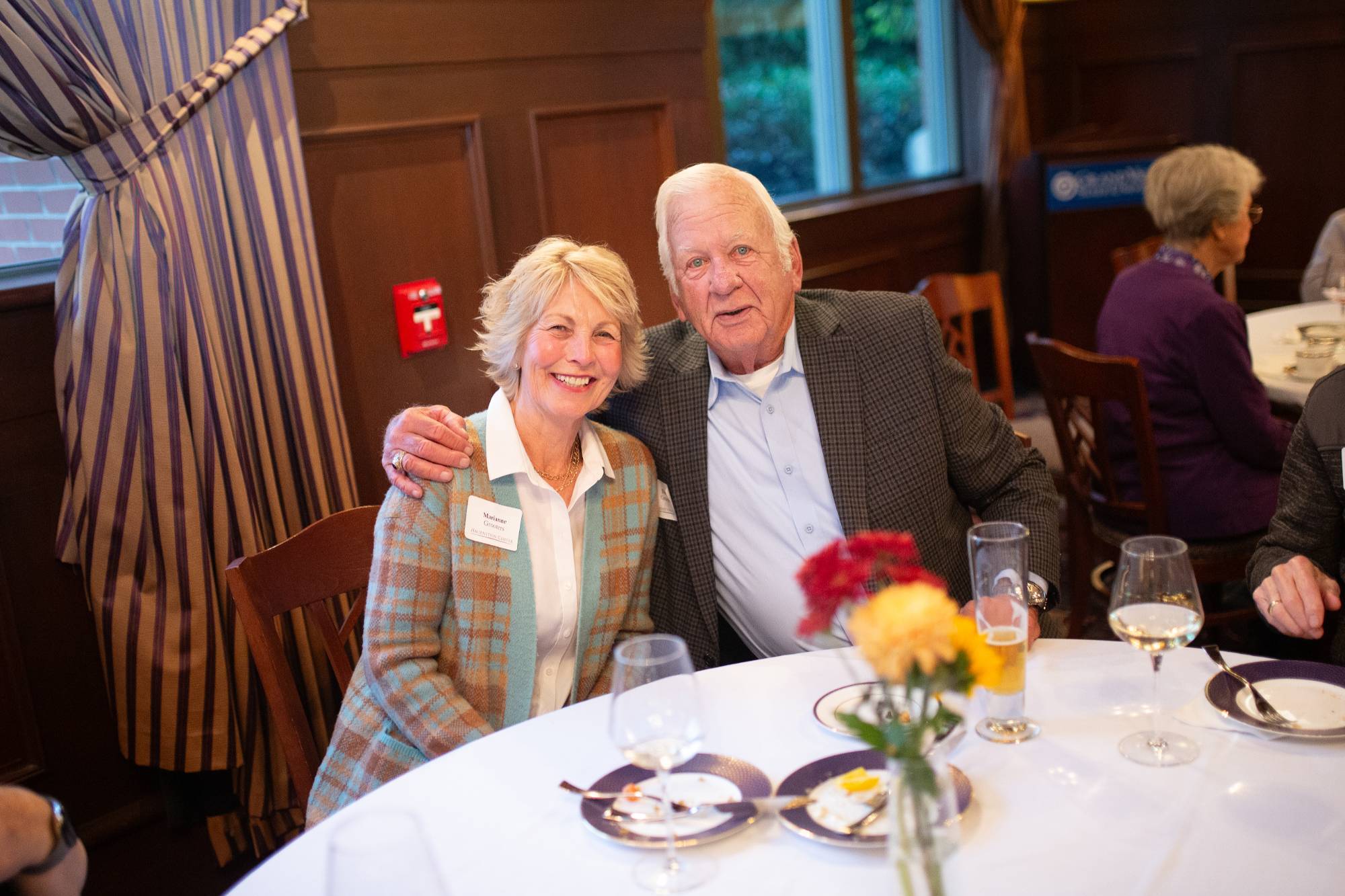 two people smile while sitting at a table